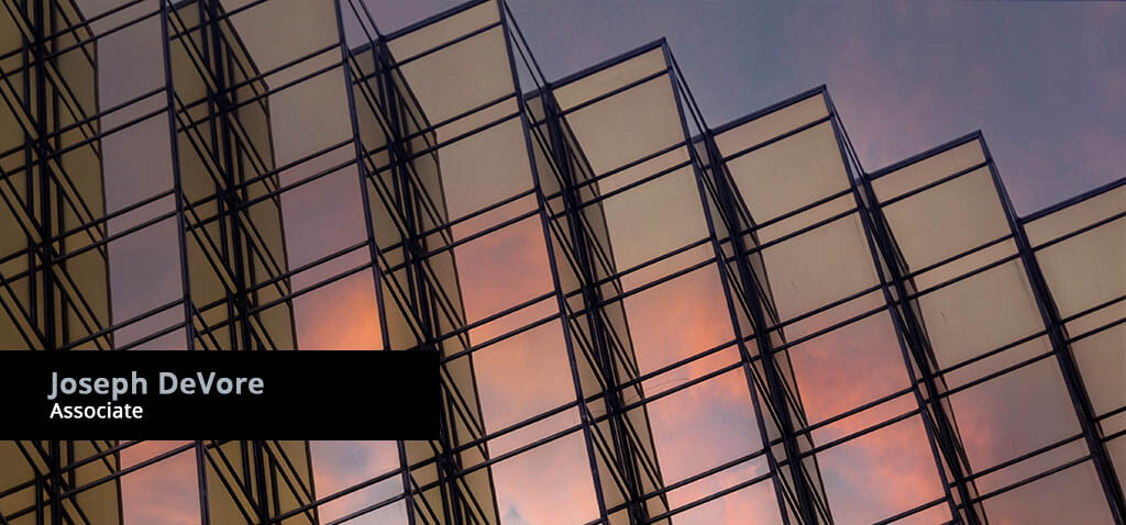 Modern building with reflective glass panels background with title banner for Joseph DeVore, Associate Attorney