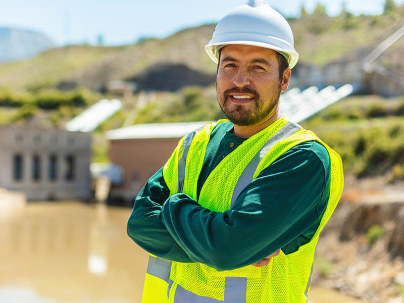 Standing profile of a male utility worker with illuminated vest on.