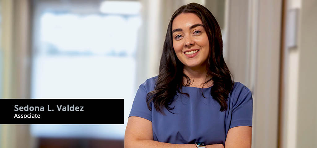 Portrait of Associate Attorney Sedona L. Valdez leaning against the wall of an office hallway.