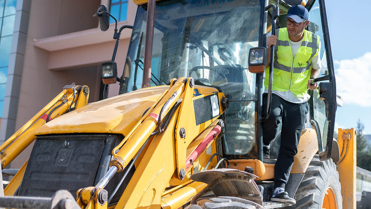 Truck operator of a front-loader falls on the steps of the truck injuring himself